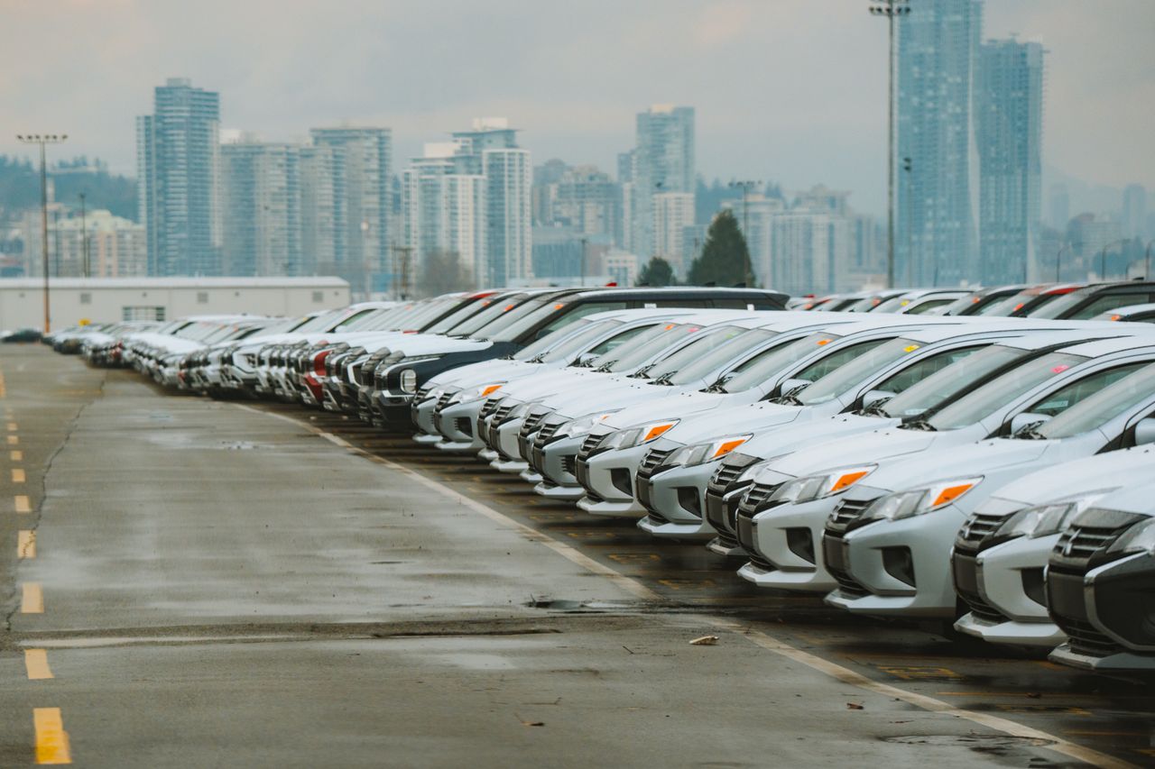 Mastering the First Impression: Your intriguing post title goes here White cars lined up in a parking lot with a city skyline backdrop.