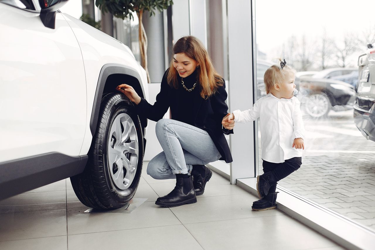 Crafting Captivating Headlines: Your awesome post title goes here Full length of cheerful smiling mother in jeans holding hands with cute little girl and looking at car wheel in car showroom in daylight